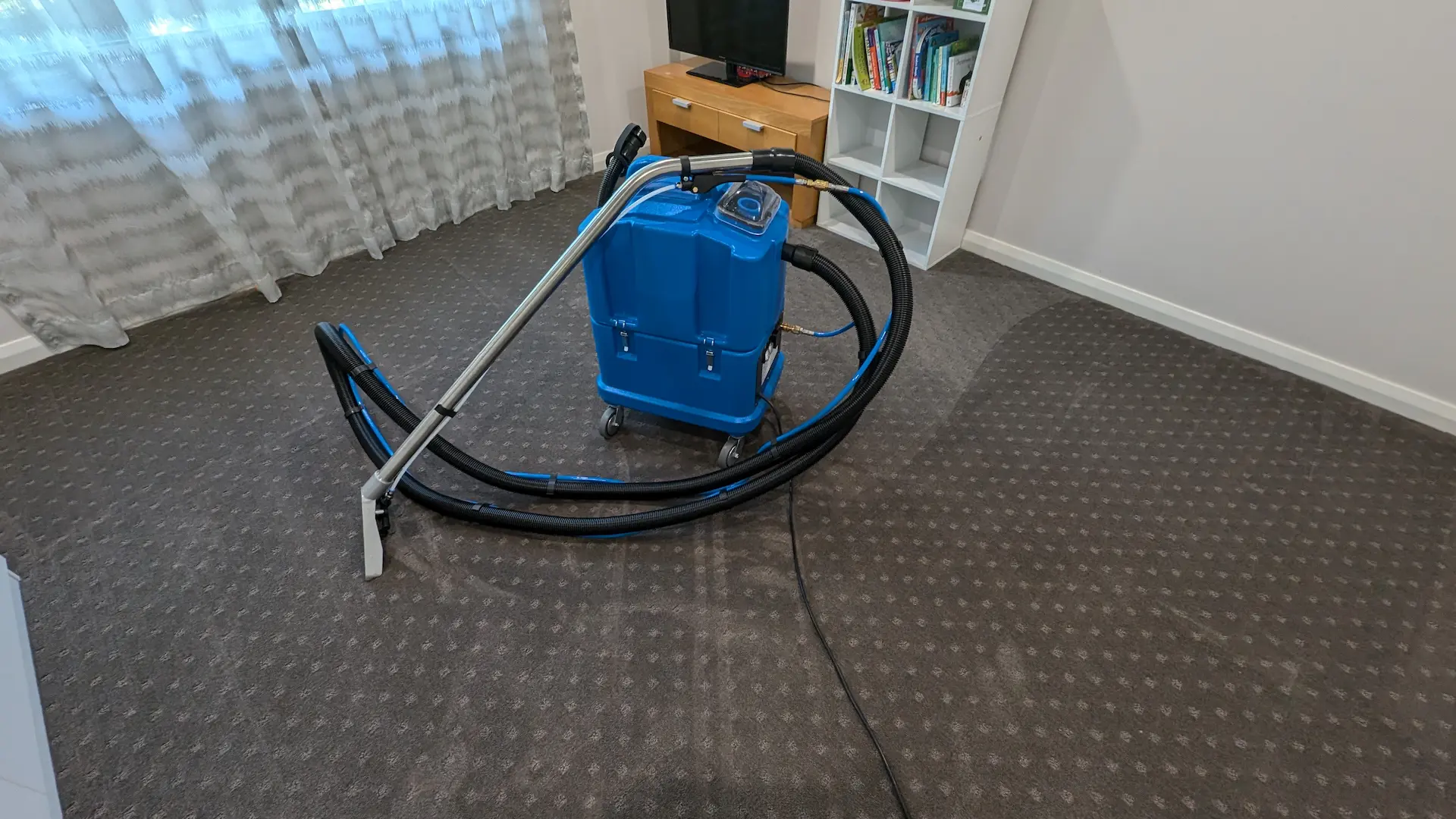 Professional hot water extraction machine at work on a living room carpet